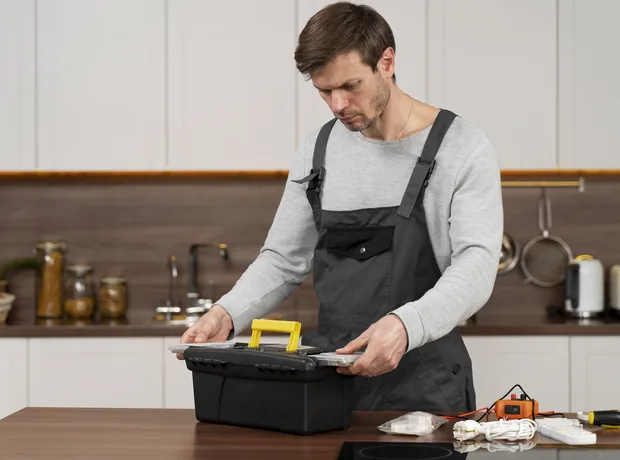Technician with a tool bag working in a kitchen