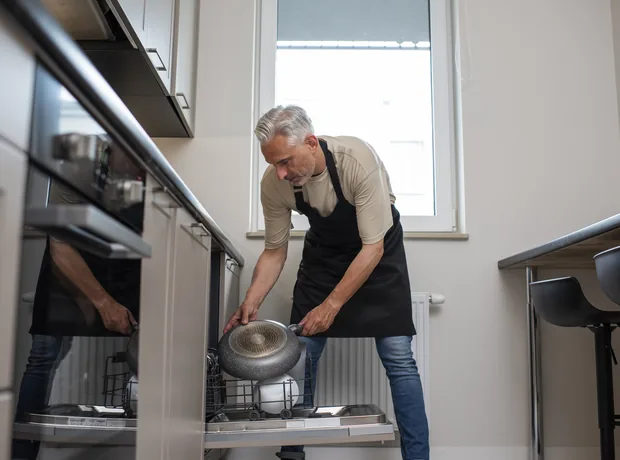 Loading a built-in dishwasher in a fitted kitchen